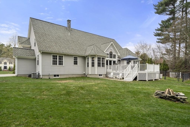 back of house with a deck, a fire pit, central AC unit, roof with shingles, and a lawn
