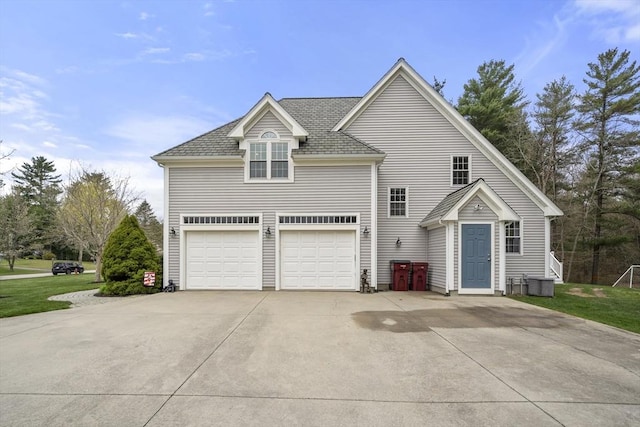 exterior space featuring concrete driveway, central air condition unit, and a garage
