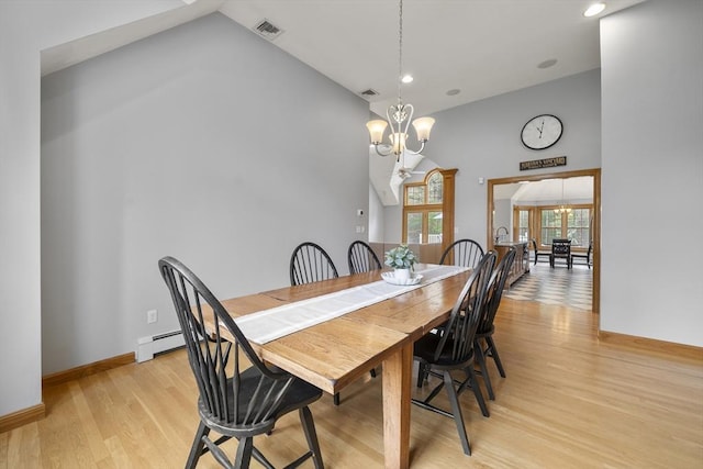 dining room with light wood-style flooring, a chandelier, visible vents, and a baseboard heating unit