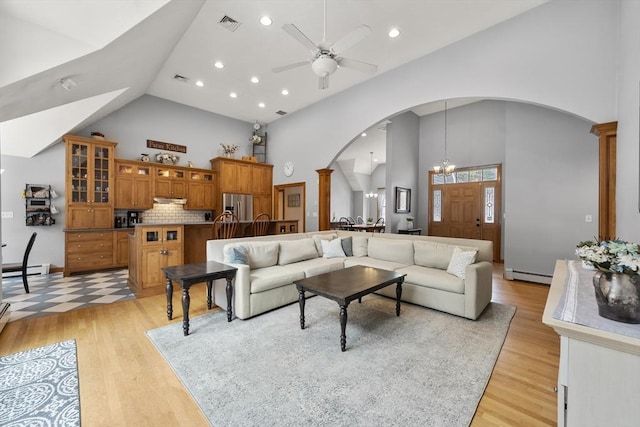 living area featuring a baseboard heating unit, light wood-style floors, high vaulted ceiling, ceiling fan, and arched walkways