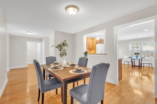 dining room with a textured ceiling and light hardwood / wood-style floors