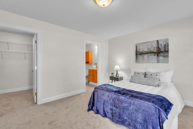 carpeted bedroom featuring a closet, a spacious closet, and connected bathroom