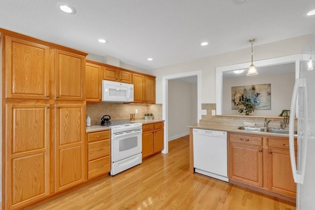 kitchen with tasteful backsplash, white appliances, pendant lighting, light hardwood / wood-style flooring, and sink