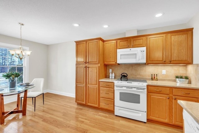 kitchen featuring decorative light fixtures, white appliances, tasteful backsplash, and light hardwood / wood-style flooring