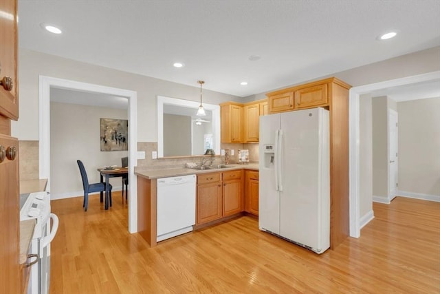 kitchen featuring backsplash, decorative light fixtures, light wood-type flooring, white appliances, and sink