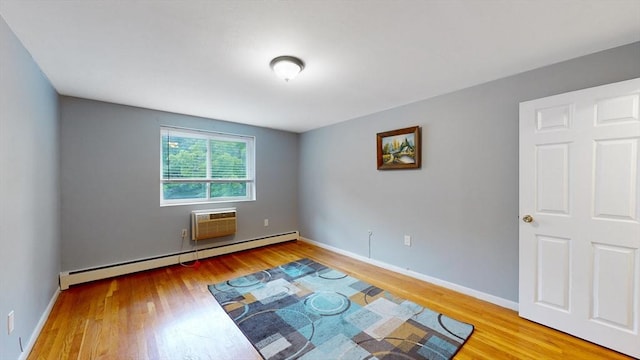 empty room with a wall unit AC, baseboards, baseboard heating, and wood finished floors