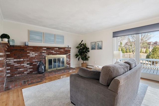 living room featuring baseboard heating, a fireplace, crown molding, and wood finished floors