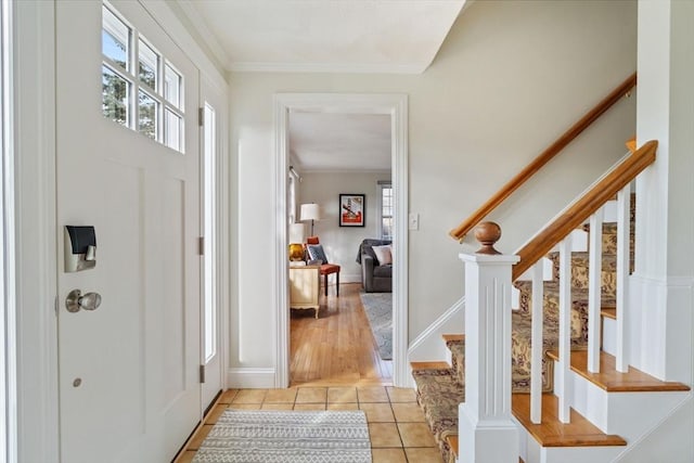 entrance foyer with light tile patterned floors, a healthy amount of sunlight, baseboards, and ornamental molding