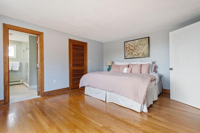 bedroom with a closet, baseboard heating, light wood-style flooring, and baseboards