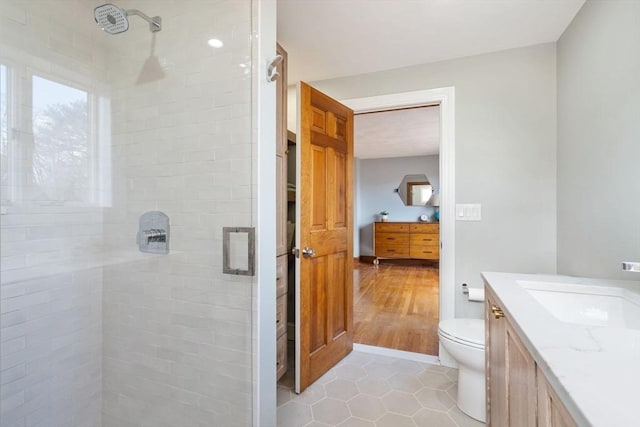 bathroom featuring tile patterned flooring, a stall shower, toilet, and vanity