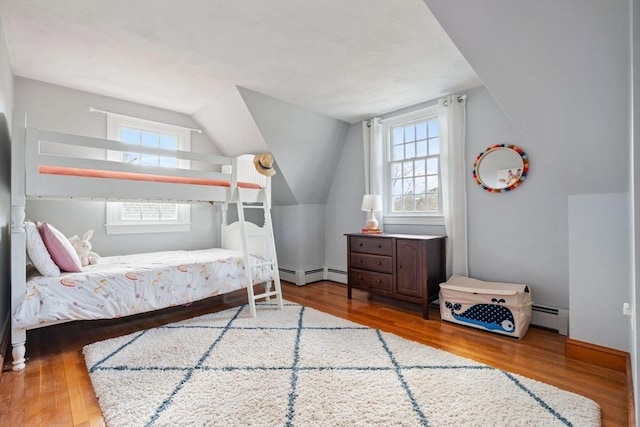 bedroom with lofted ceiling, wood finished floors, and a baseboard radiator