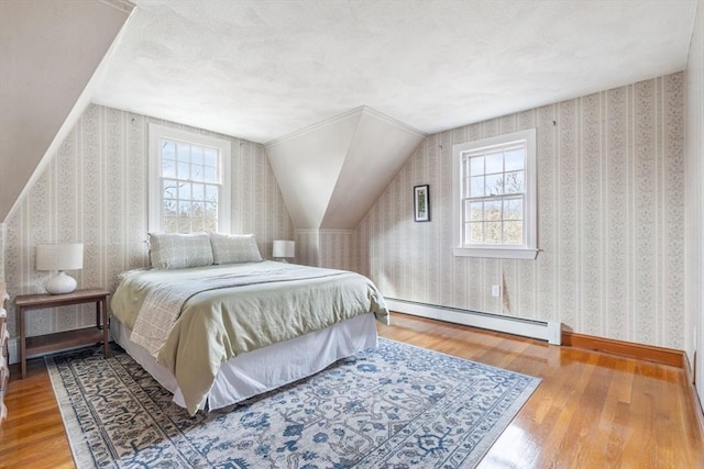 bedroom with multiple windows, wallpapered walls, and a baseboard heating unit