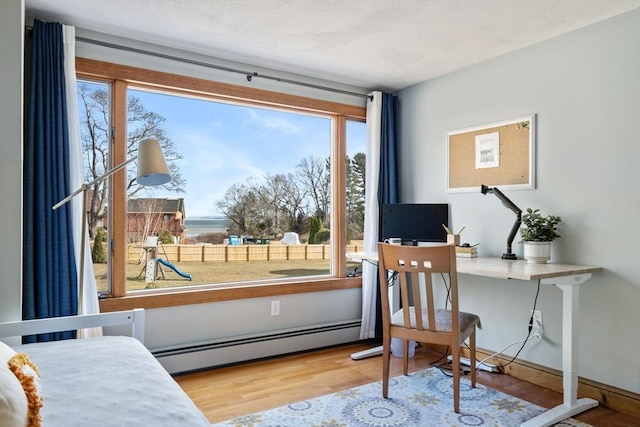 office space with a textured ceiling, a baseboard heating unit, and wood finished floors