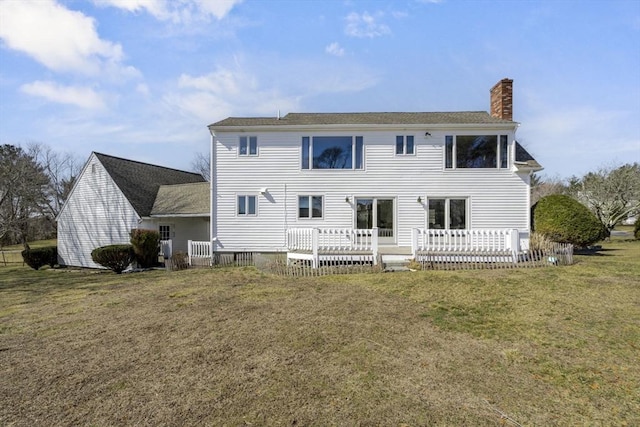 back of house with a yard, a wooden deck, and a chimney