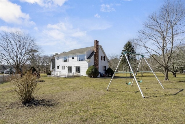 rear view of house with a playground, a yard, and a chimney