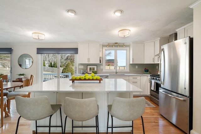 kitchen with a sink, light countertops, a kitchen bar, and stainless steel appliances