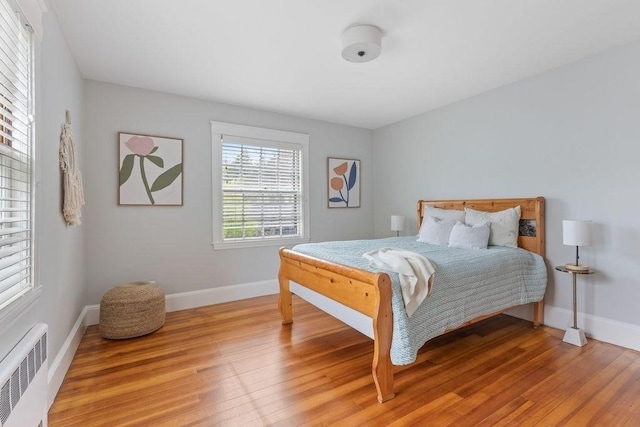 bedroom with light wood-style flooring, baseboards, and radiator heating unit