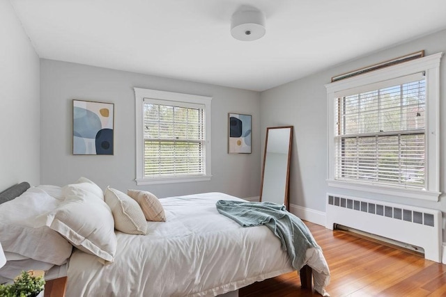 bedroom featuring radiator, wood finished floors, and baseboards