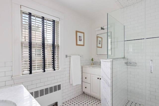 full bath featuring a stall shower, vanity, tile walls, and radiator