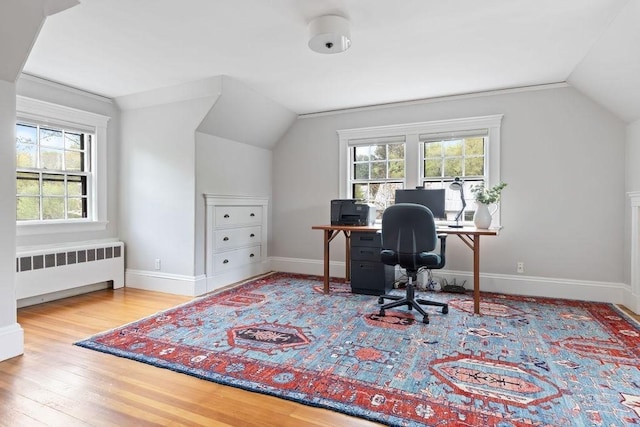 office area with lofted ceiling, a healthy amount of sunlight, and radiator heating unit