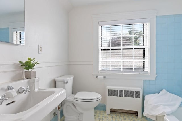 half bathroom featuring radiator, toilet, and a sink