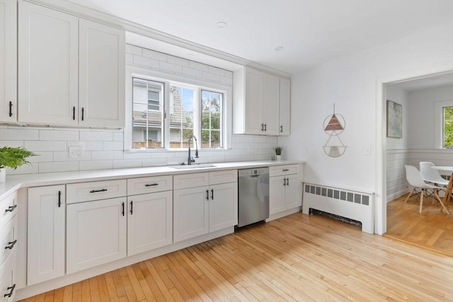 kitchen with dishwasher, radiator heating unit, a sink, decorative backsplash, and light wood-style floors