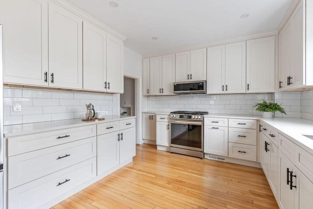kitchen featuring light countertops, appliances with stainless steel finishes, visible vents, and tasteful backsplash