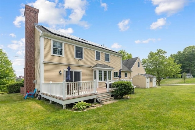 17 Maplewood Dr, Hanover, MA 02339 - back of house with a chimney, a storage unit, roof mounted solar panels, and a yard