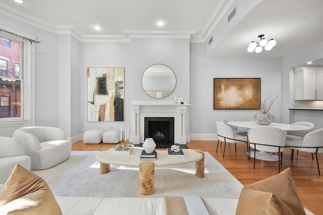 living area with wood finished floors, recessed lighting, baseboards, a fireplace with flush hearth, and ornamental molding