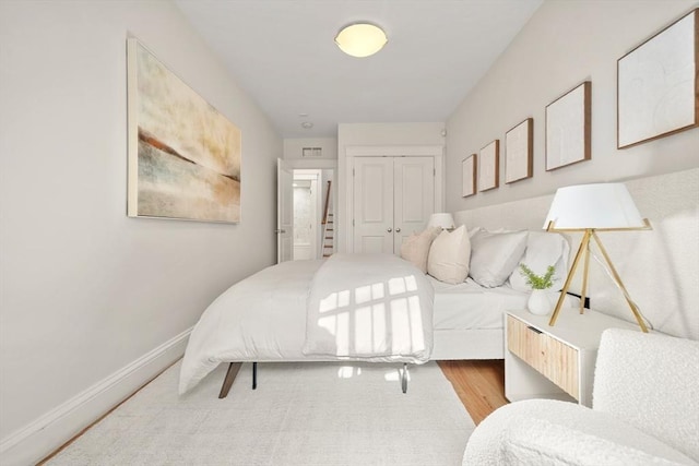 bedroom with a closet, wood finished floors, and baseboards