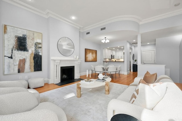 living area featuring ornamental molding, light wood-style flooring, a fireplace with flush hearth, recessed lighting, and baseboards