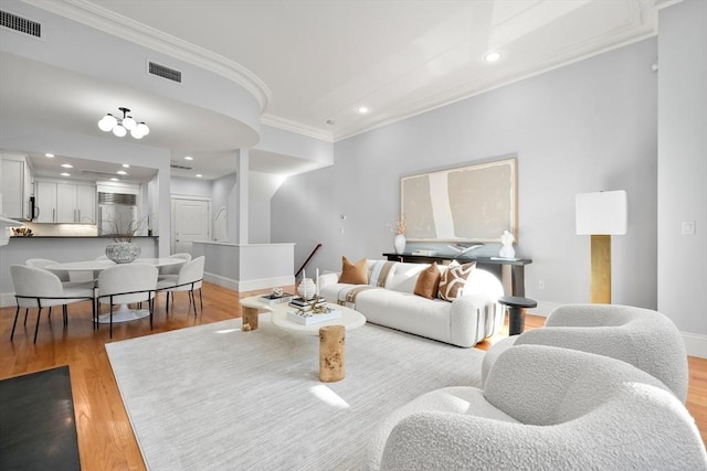 living room featuring ornamental molding, light wood finished floors, baseboards, and recessed lighting