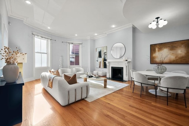 living area with crown molding, light wood finished floors, a fireplace with flush hearth, and recessed lighting