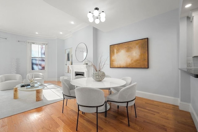 dining room featuring ornamental molding, wood finished floors, baseboards, recessed lighting, and a fireplace