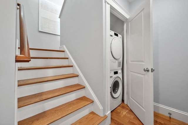 clothes washing area with stacked washer / dryer and light wood-style flooring