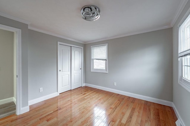 unfurnished bedroom featuring light wood-type flooring, a closet, and crown molding