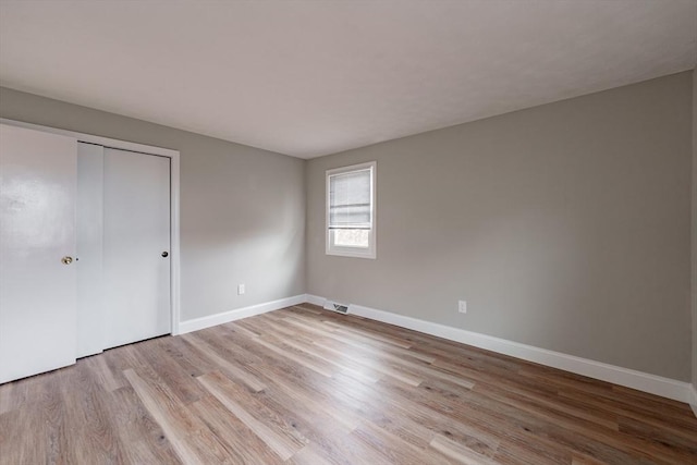 unfurnished bedroom with light wood-type flooring and a closet