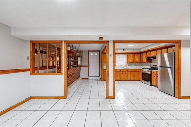 kitchen with decorative backsplash, appliances with stainless steel finishes, and light tile patterned flooring