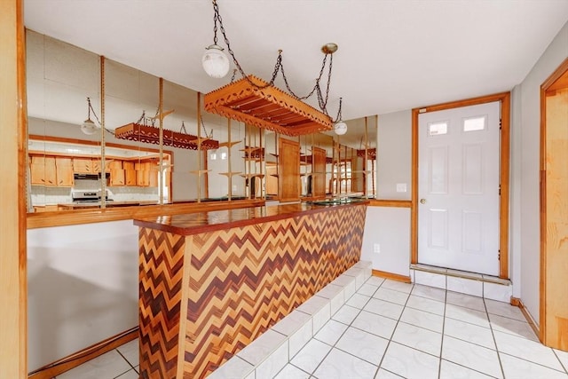 kitchen featuring electric range, hanging light fixtures, kitchen peninsula, and light tile patterned flooring