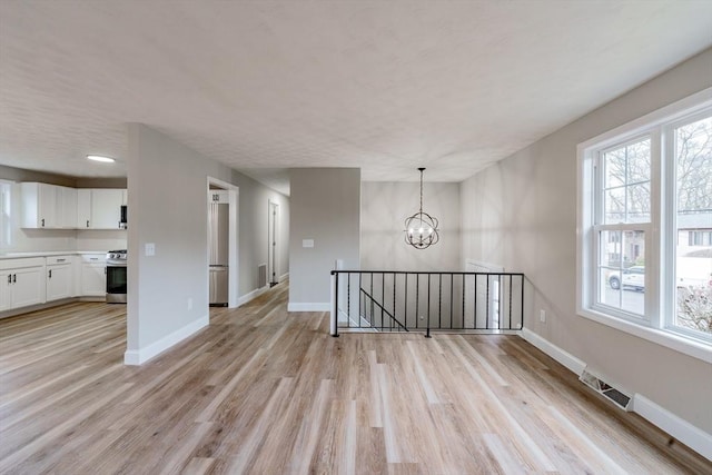 unfurnished living room with light hardwood / wood-style floors and a notable chandelier