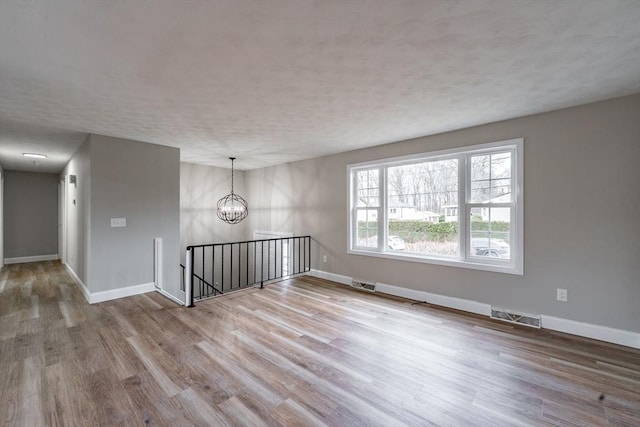 spare room featuring a notable chandelier and light wood-type flooring