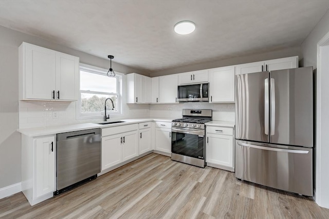 kitchen with stainless steel appliances, tasteful backsplash, pendant lighting, white cabinets, and sink