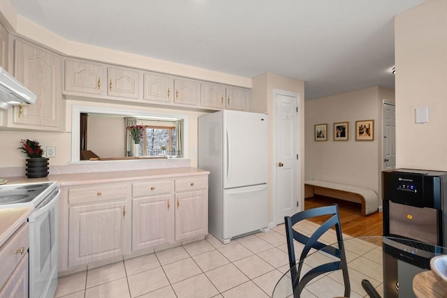 kitchen featuring range hood, white appliances, and light tile patterned floors