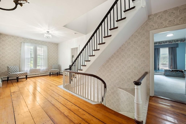 127 E St, East Bridgewater, MA 02333 - stairs featuring wallpapered walls, wood-type flooring, a chandelier, and a baseboard heating unit