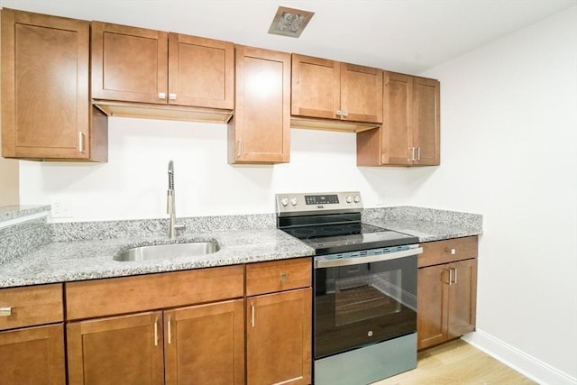 80 Main St Unit 4, Malden, MA 02148 - kitchen featuring stainless steel range with electric cooktop, a sink, light wood-type flooring, and light stone countertops