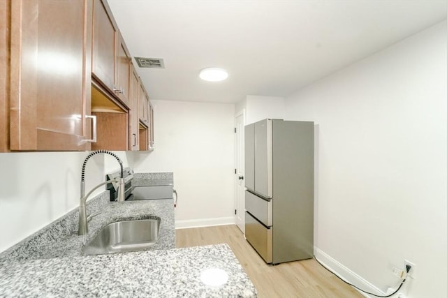 80 Main St Unit 4, Malden, MA 02148 - kitchen with stainless steel appliances, light wood finished floors, baseboards, light stone counters, and a sink