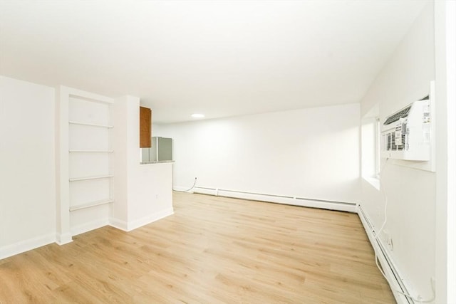 80 Main St Unit 4, Malden, MA 02148 - empty room featuring baseboard heating, light wood finished floors, baseboards, built in shelves, and an AC wall unit