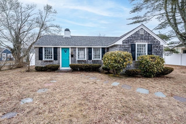 ranch-style home featuring a chimney, fence, and roof with shingles