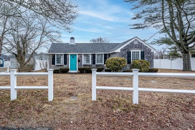 view of front of house featuring a fenced front yard, a shingled roof, and a chimney