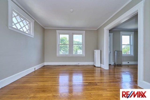 150 Nonantum St, Boston, MA 02135 - spare room with wood finished floors, radiator heating unit, baseboards, and crown molding
